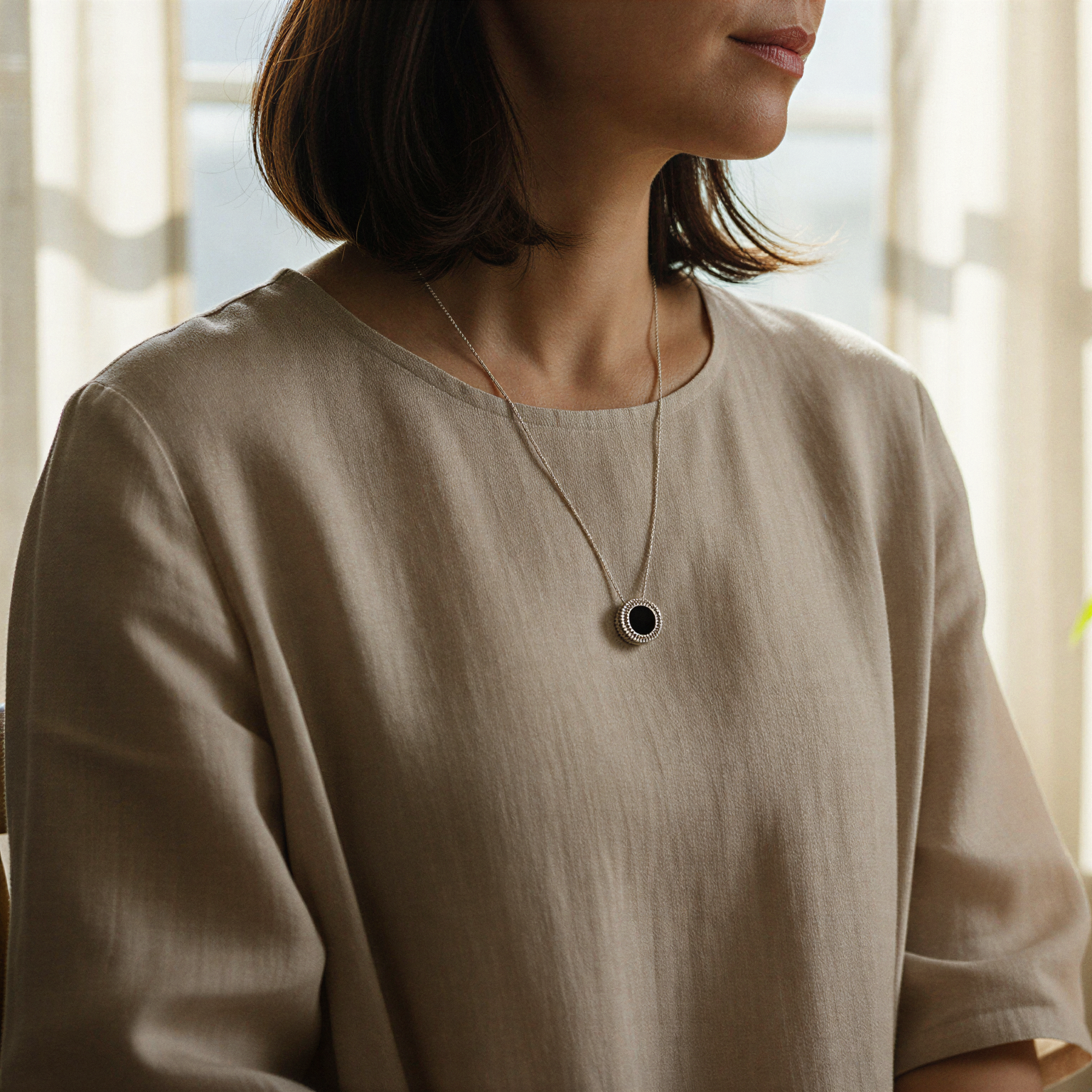 Το Joollion Elegant ως μενταγιόν, κοντά στην καρδιά, με φως που αγκαλιάζει το ασήμι.